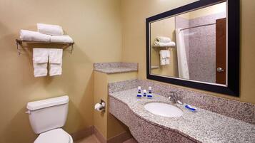 A bathroom with a toilet, sink, granite countertop, and a mirror.
