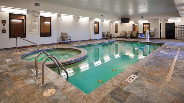 A swimming pool with a tiled deck, a lounge area with chairs, and spa rules posted on the wall. - Best Western Plus Desoto Inn & Suites (Mansfield)