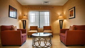 A room with two sofas, a round table, and two chairs. There are two lamps on either side of the window. - Best Western Plus Desoto Inn & Suites (Mansfield)