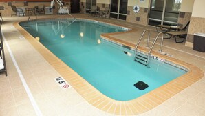 An indoor swimming pool with clear water, marked depth lines, and a lifeguard chair.