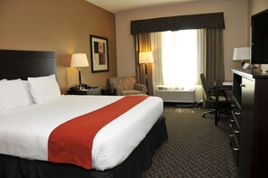 A hotel room with a large bed, a desk, a chair, and a television.