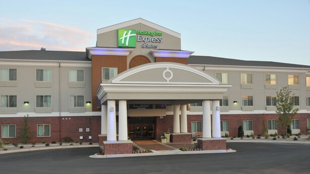 A Holiday Inn Express & Suites hotel with a covered entrance, multiple windows, and a brick facade.