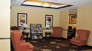A hotel lobby with seating, a photo display, and a business center sign.