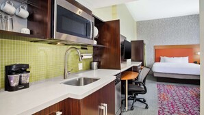 A compact hotel room with a kitchenette, a bed, a desk, and a TV. - Home2 Suites by Hilton San Antonio Downtown - Riverwalk, TX (San Antonio)