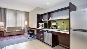 A compact hotel kitchen with a sofa, a desk, a dishwasher, a microwave, a refrigerator, and a sink. - Home2 Suites by Hilton San Antonio Downtown - Riverwalk, TX (San Antonio)