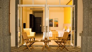 A hotel room with a stone archway entrance, a checkered floor, and two rocking chairs facing a bed with a white bedspread and pillows. - Papago International Resort (Chishang)