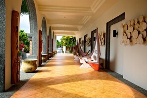 A corridor with a tiled floor, wooden columns, and a row of traditional boats against the wall.