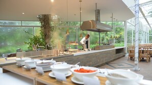 A modern kitchen with a chef preparing food, large windows, and a variety of dishes on the counter. - Papago International Resort (Chishang)