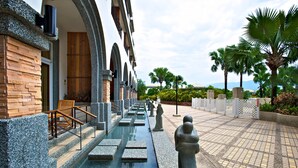 A pathway leading to a building with a stone facade and wooden accents, flanked by palm trees and a clear sky. - Papago International Resort (Chishang)