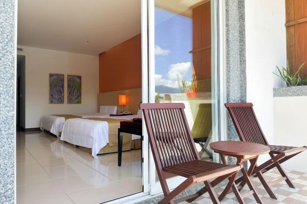 A hotel room with a bed, a desk, and two chairs.