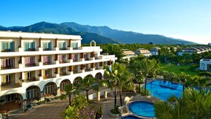 A hotel with multiple balconies, a swimming pool, and a view of mountains. - Papago International Resort (Chishang)