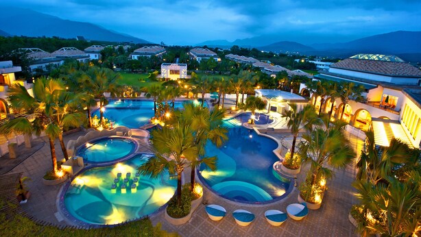 A resort with multiple swimming pools, palm trees, and a mountainous backdrop. - Papago International Resort (Chishang)
