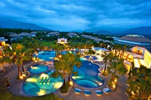 A resort with multiple swimming pools, palm trees, and a mountainous backdrop. - Papago International Resort (Chishang)