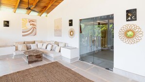 A modern living room with a wooden ceiling, a glass door leading to a balcony, and various wall art.