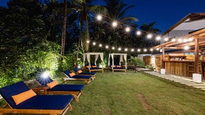 A well-lit outdoor area with lounge chairs and a bar area.