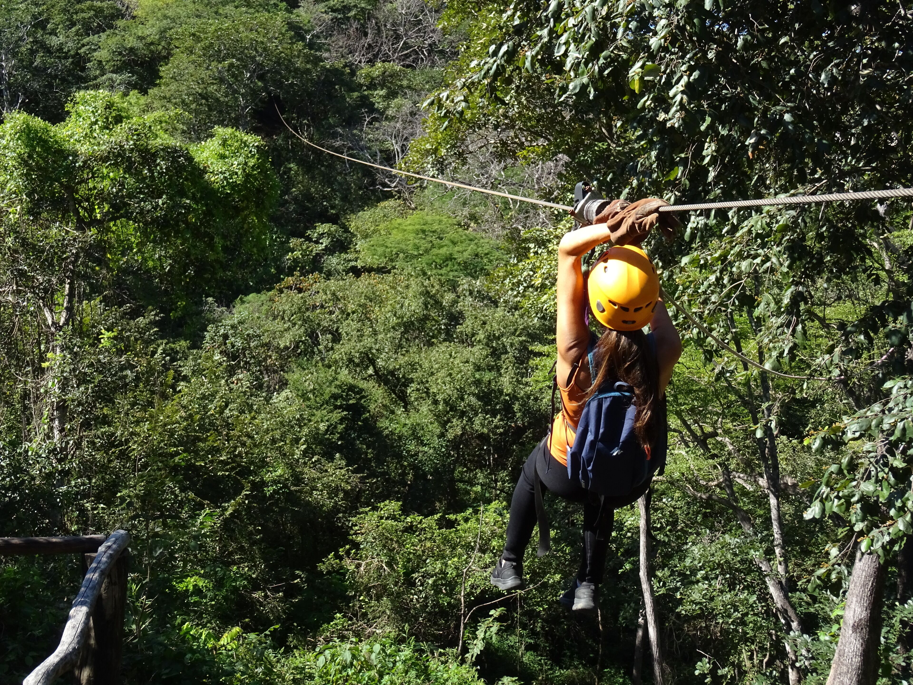 Eine Person befindet sich in einem bewaldeten Gebiet auf einer Zipline.