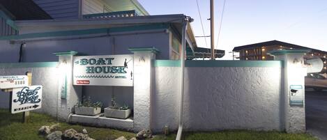 A building with a sign reading "Boat House" and a small garden area with rocks and plants.