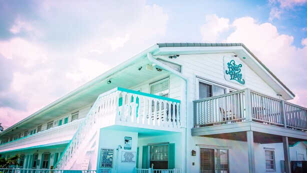 A white building with a sign reading "Boat House" and a balcony with a railing.