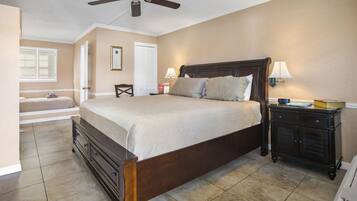 A bedroom with a bed, bedside tables, a ceiling fan, a window with blinds, and a door.