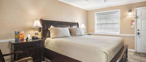 A bedroom with a bed, nightstands, a chair, a ceiling fan, and a window with blinds.