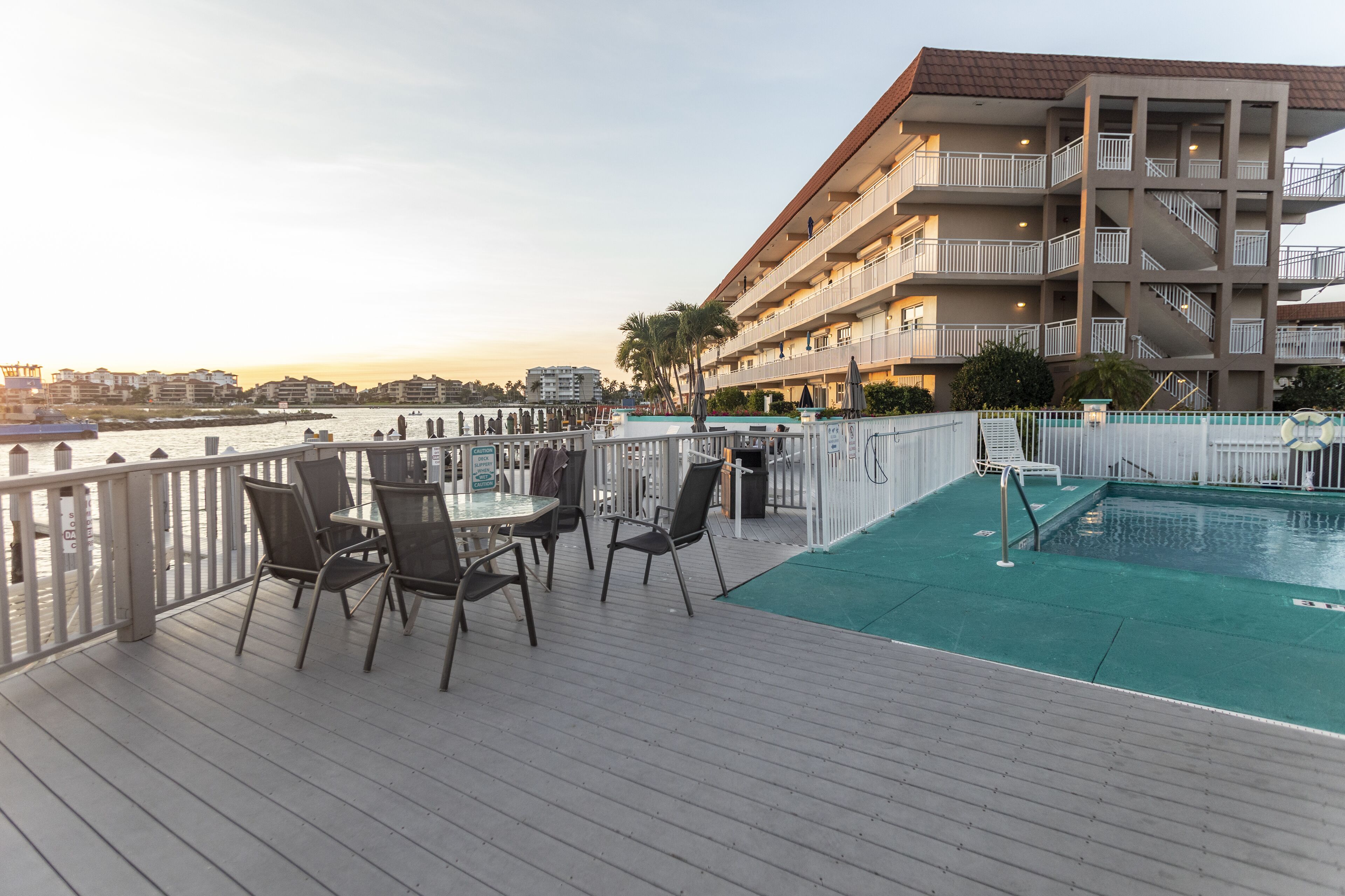 Un espace piscine aménagé sur le toit, offrant une vue sur les gratte-ciel de la ville et un grand bâtiment doté de nombreux balcons.