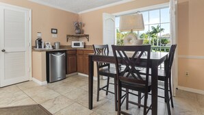 A kitchen with a dining table, chairs, a microwave, and a coffee maker. - The Boat House (Marco Island)
