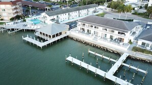 An aerial view of a waterfront property with a large building featuring multiple balconies and a dock extending into the water. - The Boat House (Marco Island)