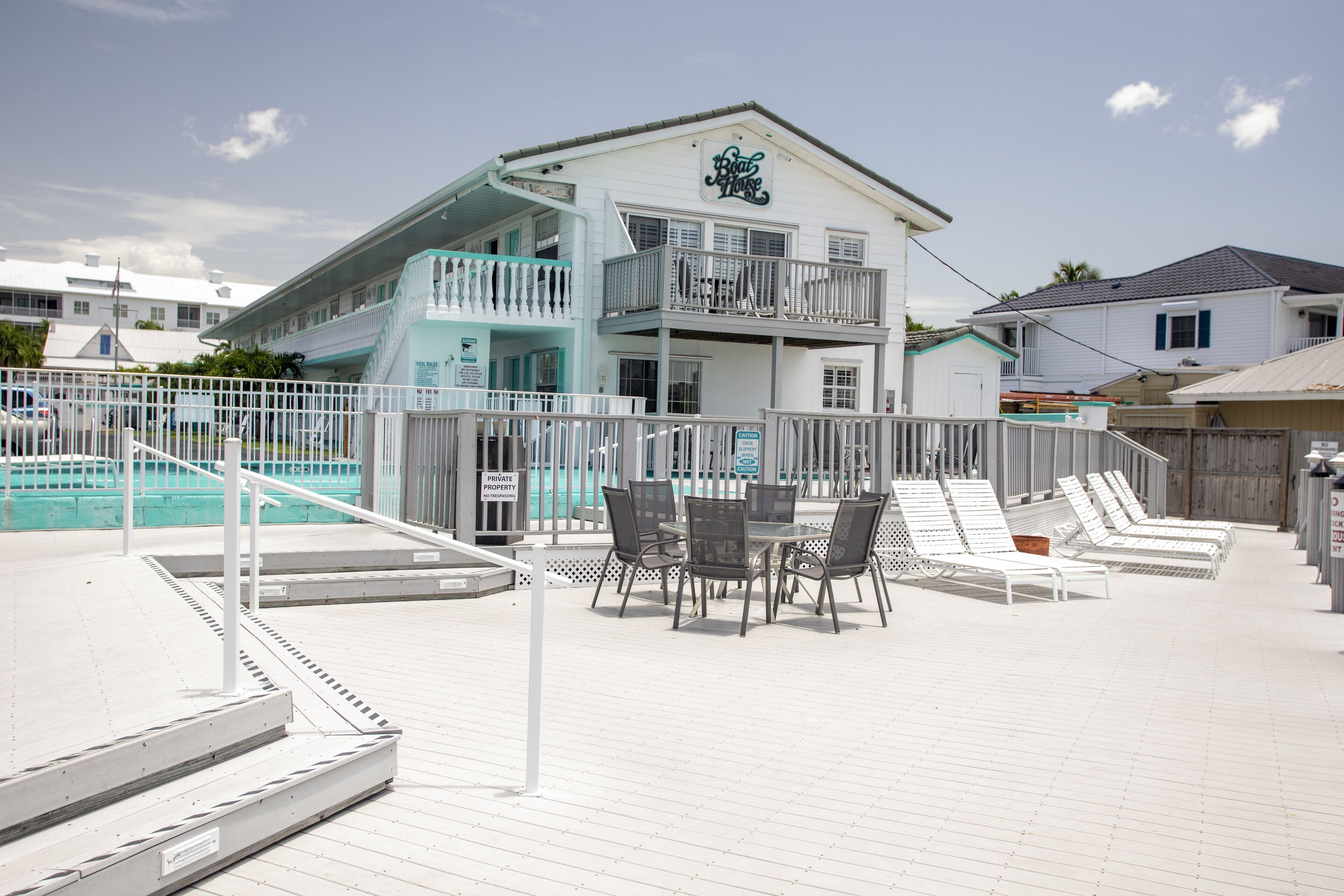 Hotel amb vistes a la platja, zona de piscina, seients exteriors i un senyal que indica propietat privada.