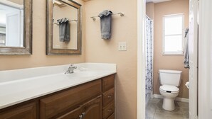 A bathroom with a wooden vanity, a white sink, a mirror, and a toilet.