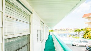 A corridor with a green floor, white walls, and a white balcony railing.