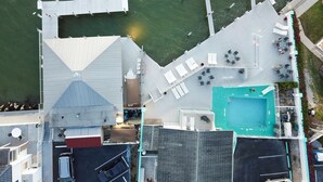 An aerial view of a waterfront property with a swimming pool, outdoor seating, and a dock. - The Boat House (Marco Island)
