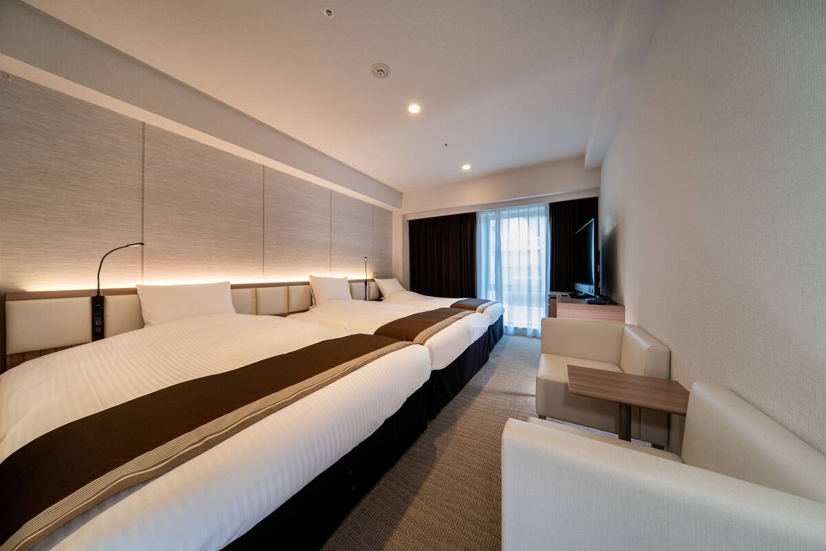 Une chambre d’hôtel moderne, dotée d’un grand lit, d’un bureau et d’une télévision.