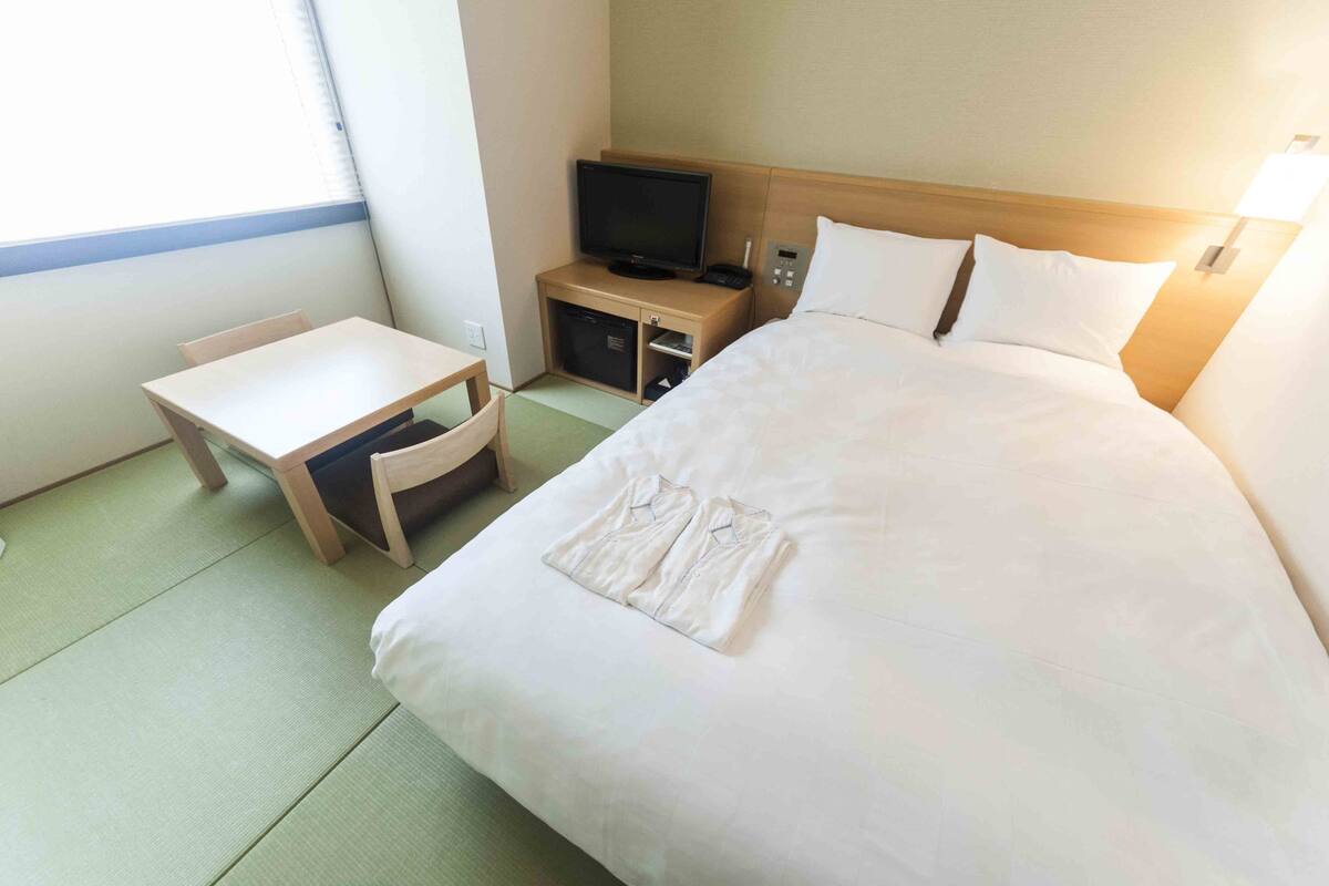 Une chambre d’hôtel avec un lit, un bureau, une télévision et un petit placard.