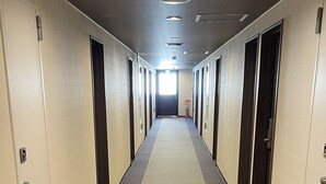 Un long couloir étroit, avec des portes des deux côtés, qui mène à des pièces individuelles.
