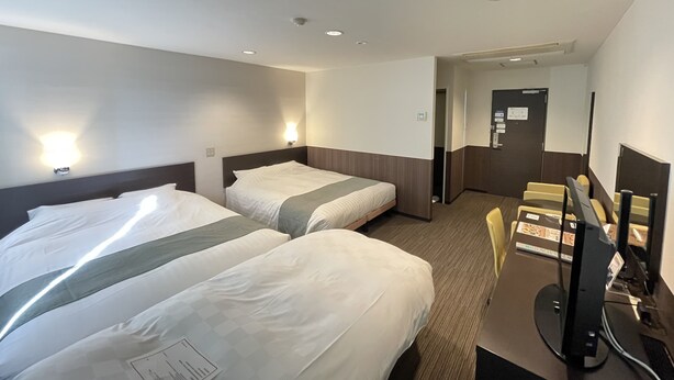 Une chambre d’hôtel avec deux lits, un bureau avec un ordinateur et un miroir.