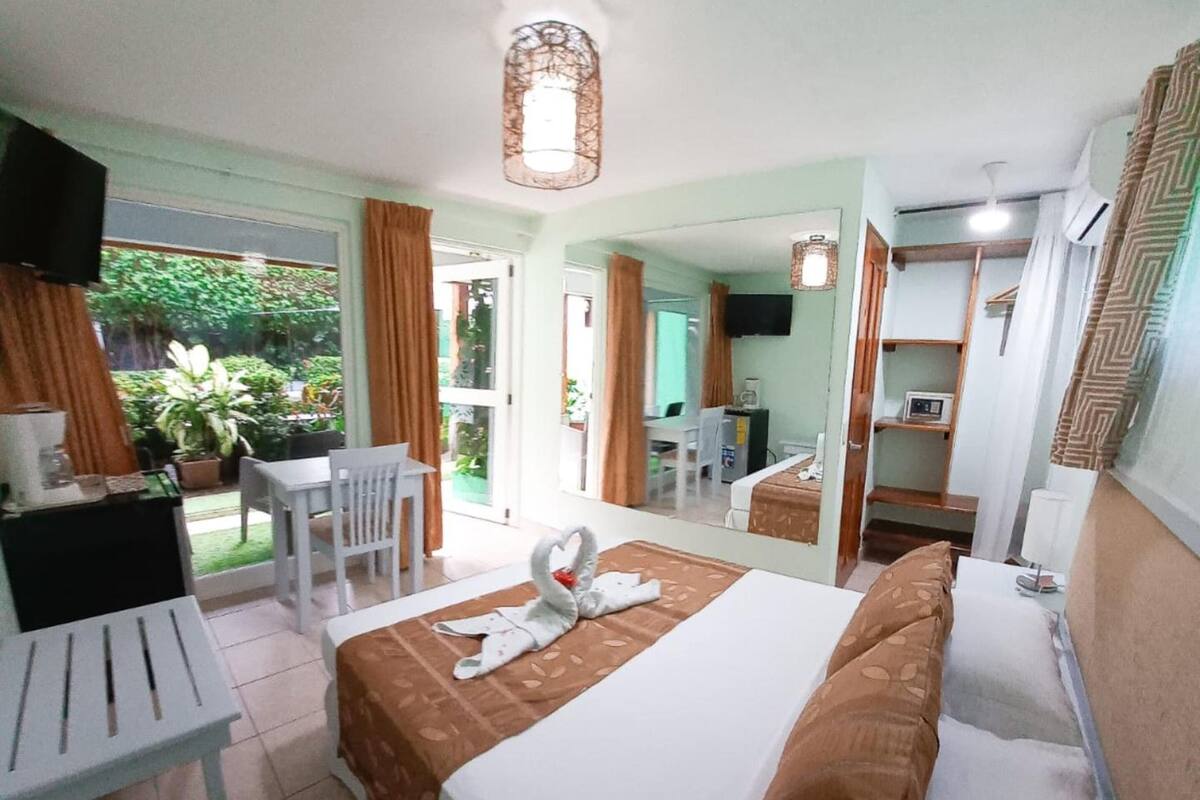 Habitación de hotel con cama, escritorio, silla, televisión y vistas al exterior.
