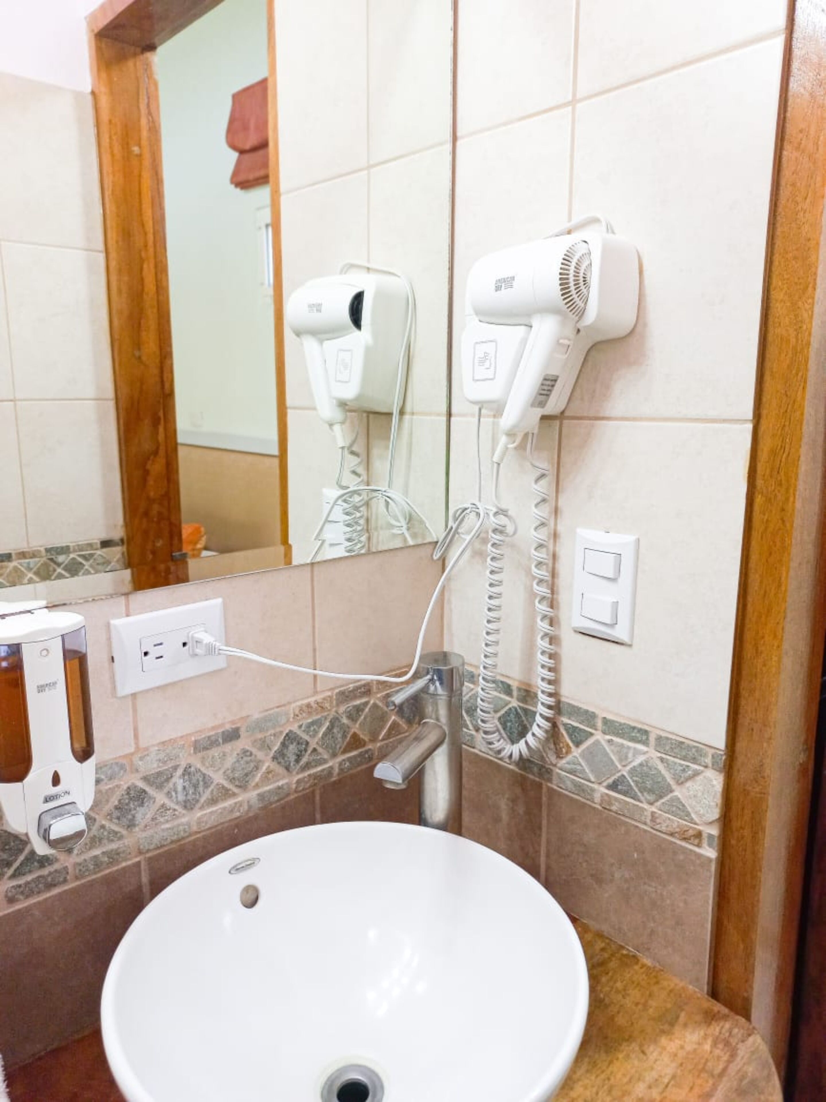 A bathroom with a white sink, a hairdryer, and a mirror.
