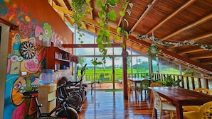 Una habitación amplia con techo de madera, un ventanal con vistas al exterior y equipo de ejercicio.