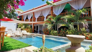 Un hotel con piscina, sillones de descanso y plantas tropicales.