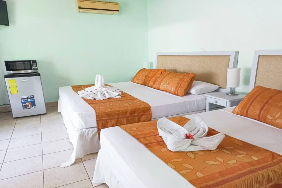 Habitación de hotel con dos camas, un minibar y un televisor.