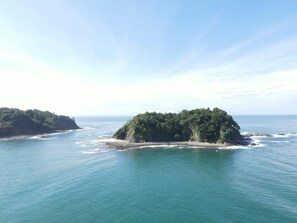 A coastal landscape with two islands, one larger and one smaller, surrounded by clear blue waters.