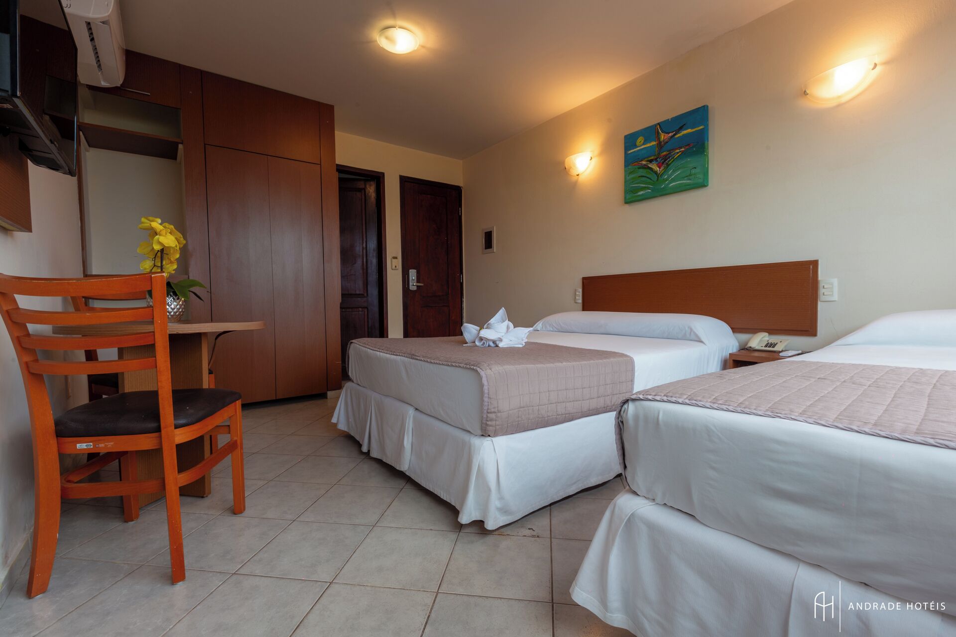 A hotel room with two beds, a desk, and a chair.