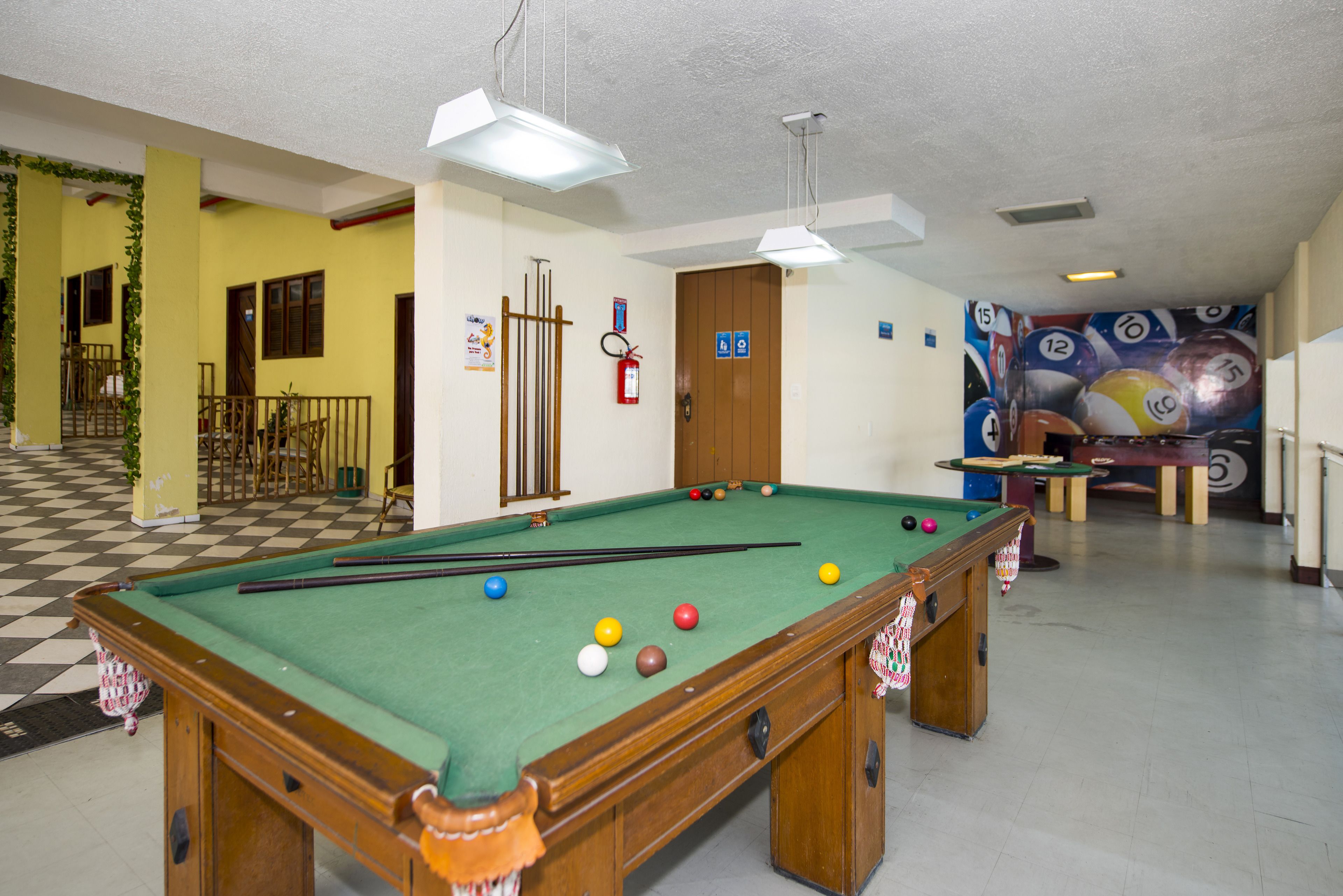 A pool table with balls, a fire extinguisher, and a door with accessibility signs.
