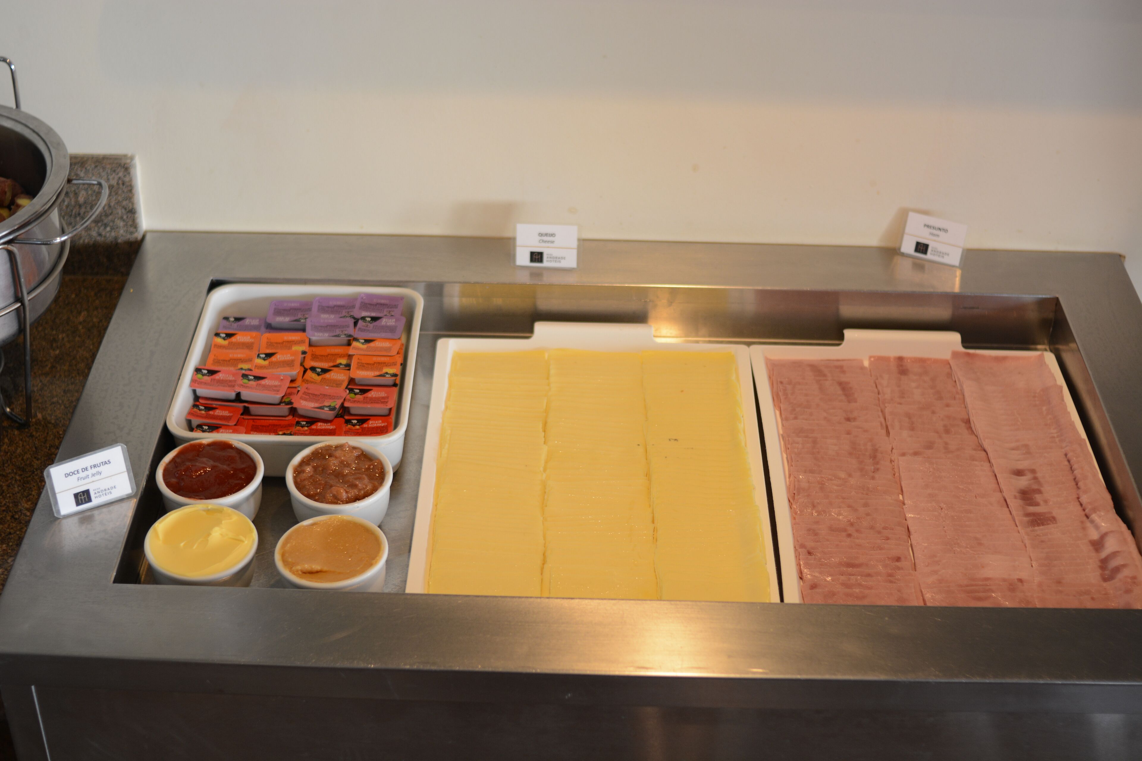Um buffet com diversas opções de comida, incluindo diferentes queijos, carnes e molhos.