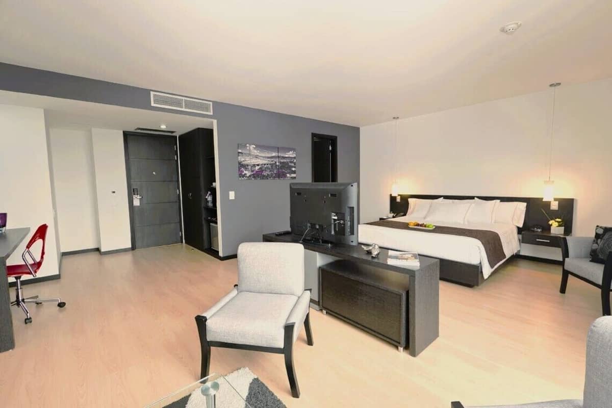 Een moderne hotelkamer met een bed, bureau, stoel en televisie.