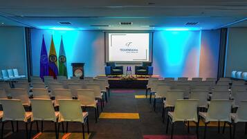A conference room with rows of white chairs, a podium, and a projection screen displaying 'TEQUENDAMA HOTEL MEDELLIN'.