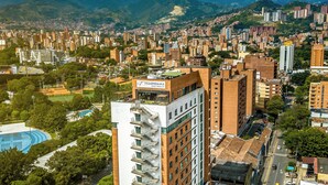 Un hôtel de grande hauteur, avec de nombreux étages, une piscine sur le toit et une vue sur le paysage urbain et les montagnes.