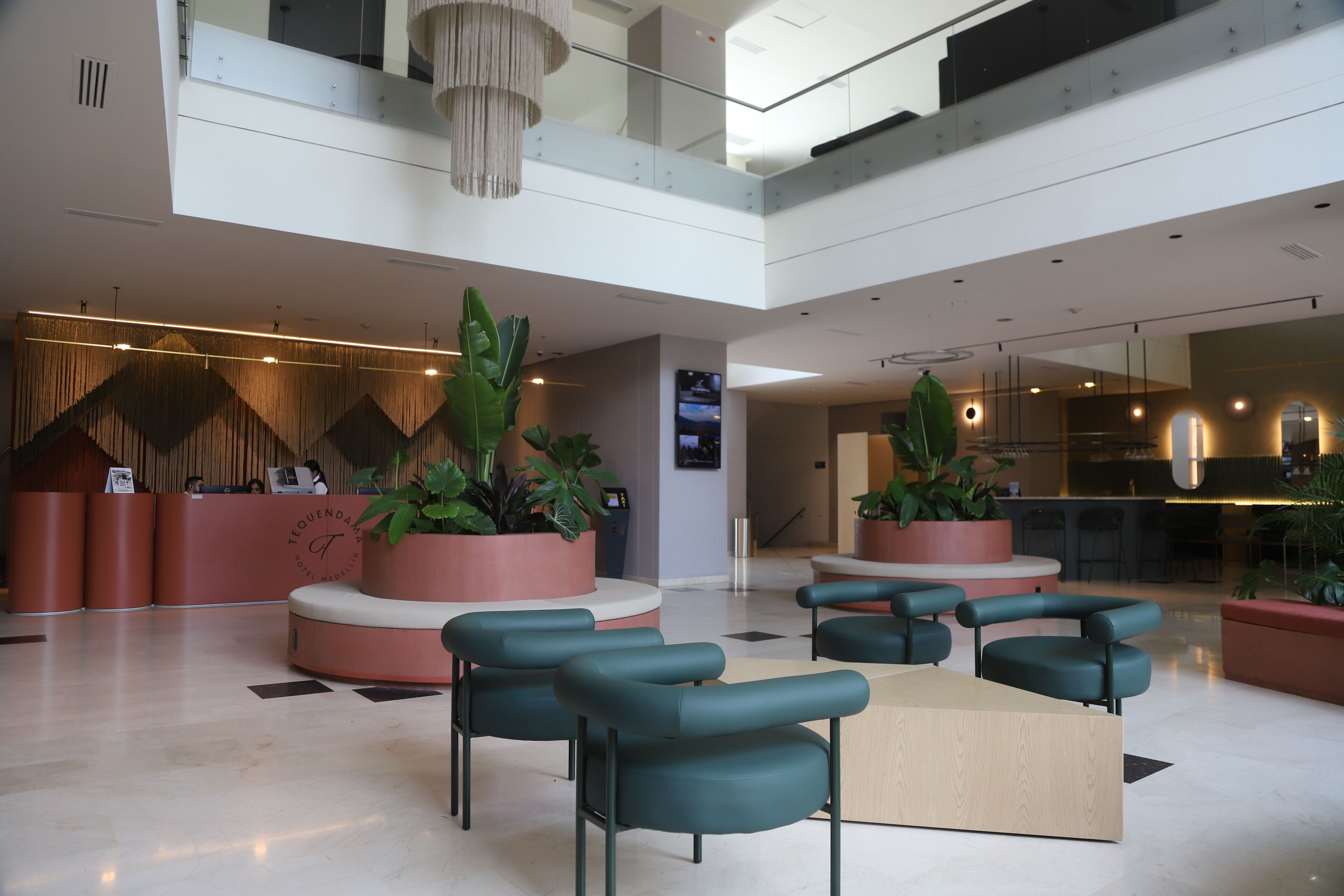 Un vestíbulo moderno con mostrador de recepción, zona de estar y plantas en macetas.