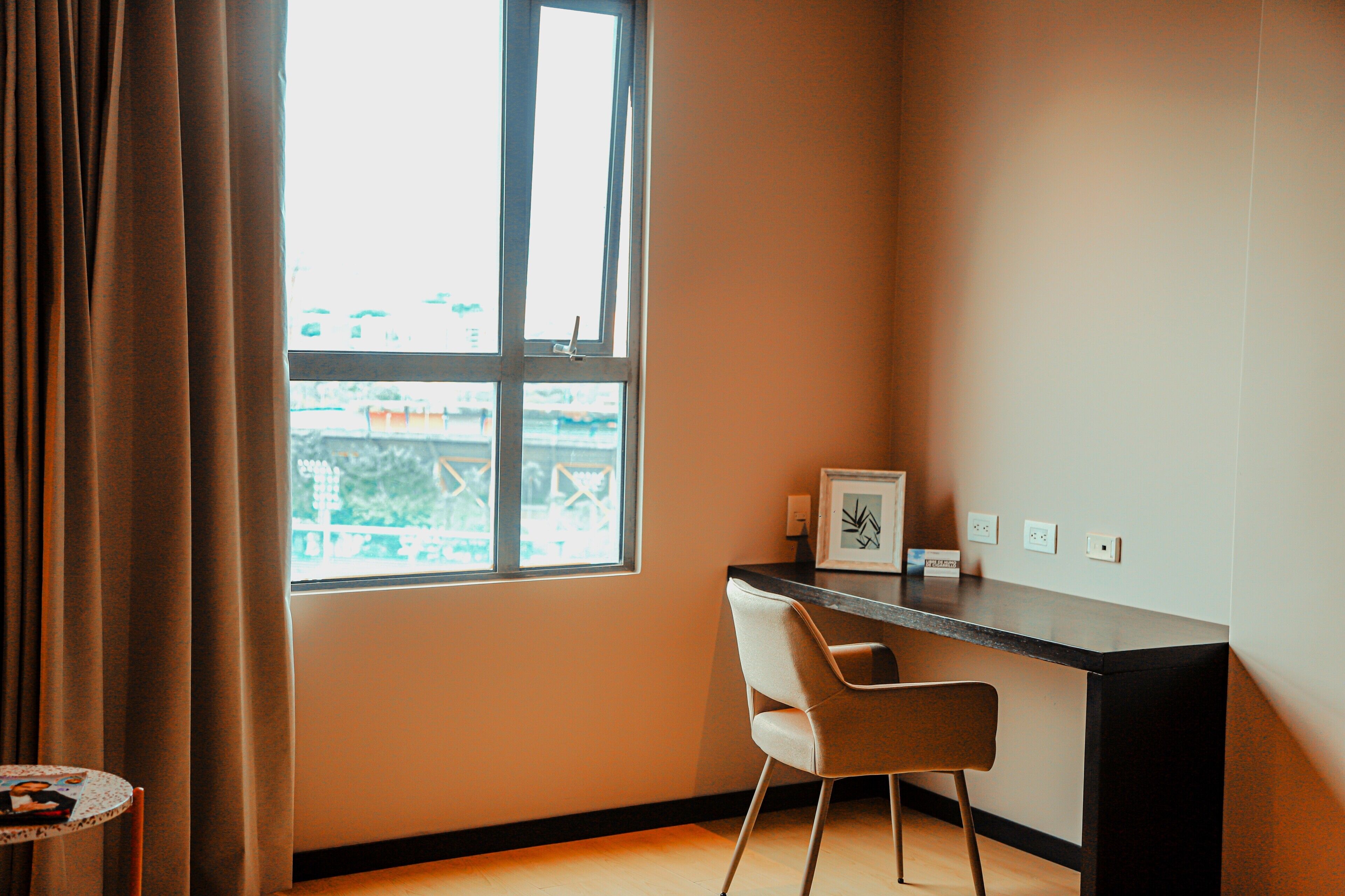 A room with a desk, chair, and a window with curtains.
