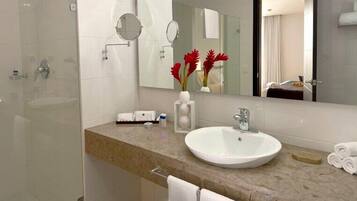 Un baño moderno con cabina de ducha de vidrio, lavamanos blanco y un espejo grande.